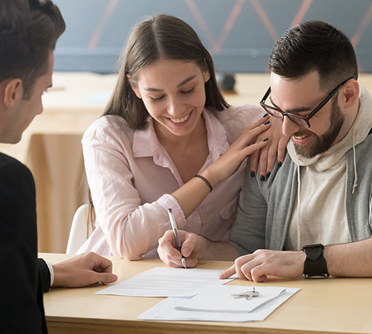 Smiling couple signing closing documents at the close of escrow